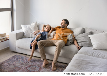 Dad and his little daughter settled down comfortable on couch Dad and his little daughter settled down comfortable on couch 123922443