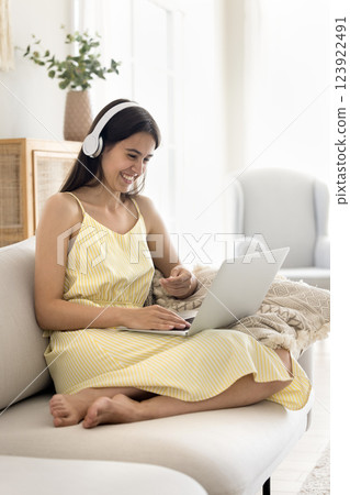 Cheerful young female wearing headphones chatting by videocall on notebook 123922491