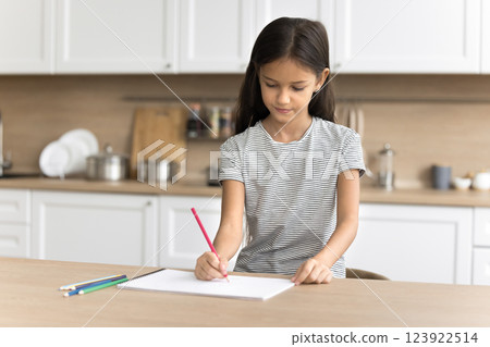 Preteen age girl create pencil drawing on large kitchen table 123922514