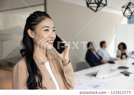 Happy Asian business woman talking on mobile phone in office 123922573
