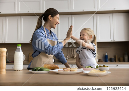 Daughter happily gives high five to mom in kitchen 123922624