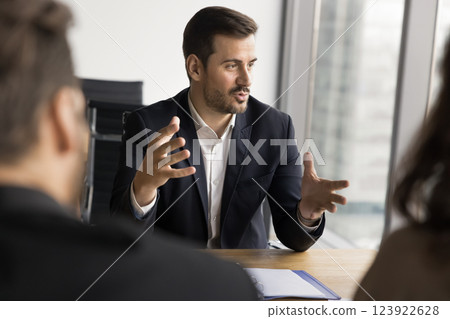 Businessman makes speech sits at table in front of shareholders Businessman makes speech sits at table in front of shareholders 123922628