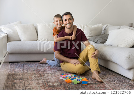 Dad and son sit on rug in cozy living room 123922706