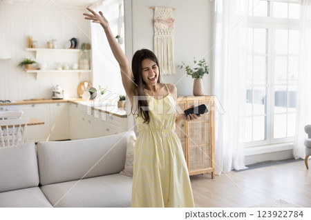 Overjoyed young girl dance at home to music on smartphone Overjoyed young girl dance at home to music on smartphone 123922784