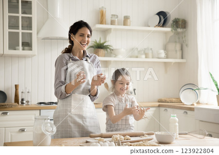 Laughing mum little daughter rolling dough clapping hands in flour Laughing mum little daughter rolling dough clapping hands in flour 123922804