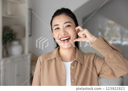 Cheerful excited young adult Asian girl showing half heart hand Cheerful excited young adult Asian girl showing half heart hand 123922821