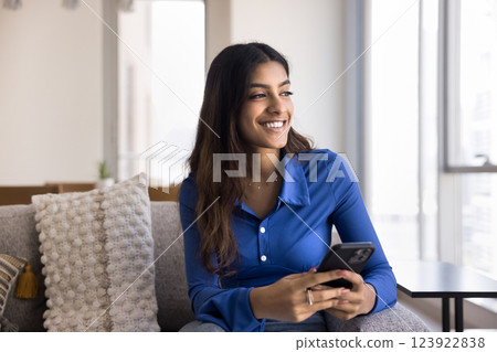 Indian female holding smartphone with thoughtful expression Indian female holding smartphone with thoughtful expression 123922838