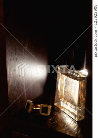 A luxurious perfume bottle with elegant cufflinks on a luminous background  123922900