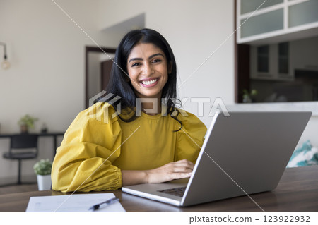 Portrait of happy Indian woman sits at table with laptop 123922932