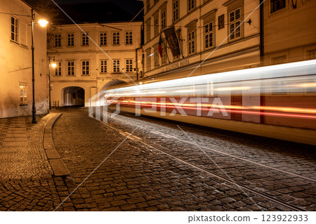A quiet night on Letenska Street reveals blurred tram lights speeding through a tunnel. The cobblestones shine under street lamps casting a warm glow across the Lesser Town. 123922933
