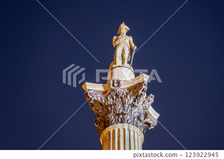 Nelson's Column stands tall in Trafalgar Square, beautifully illuminated against the night sky. The statue of Admiral Nelson commands attention, surrounded by historic architecture. 123922945