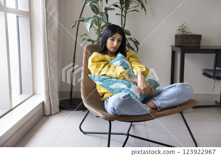 Indian woman sits in armchair looks melancholic, upset and unhappy 123922967