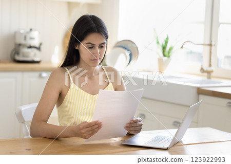 Young woman thinking over paper documents at home office desk Young woman thinking over paper documents at home office desk 123922993