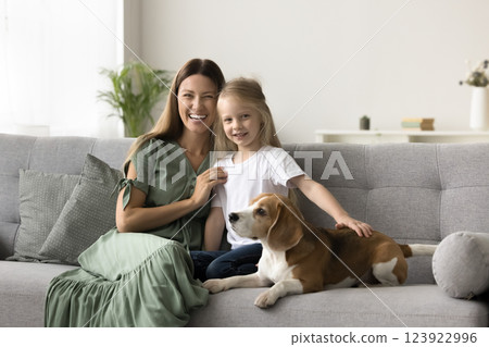 Young woman and daughter sitting on sofa with dog 123922996