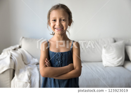 Little girl standing in living room with her arms-crossed Little girl standing in living room with her arms-crossed 123923019
