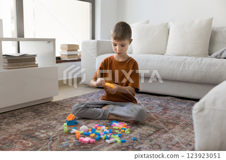 Cute boy playing colorful blocks seated on floor at home Cute boy playing colorful blocks seated on floor at home 123923051