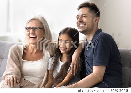 Cheerful family grandma dad grandchild hug on sofa look aside 123923096