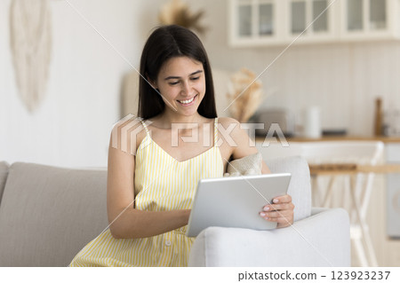 Smiling young woman use tablet computer on sofa at home 123923237