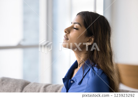 Young 20s Indian woman sitting on sofa with eyes closed 123923292