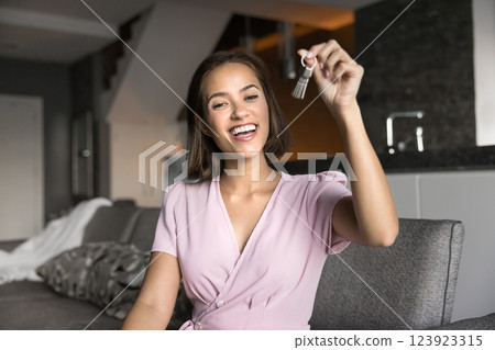 Overjoyed woman showing bunch of keys seated on couch 123923315