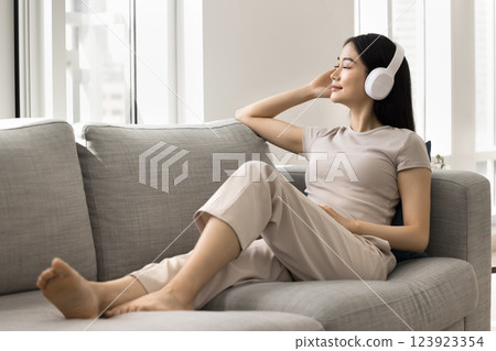 Young 25s Asian relaxed woman relish favourite music Young 25s Asian relaxed woman relish favourite music 123923354