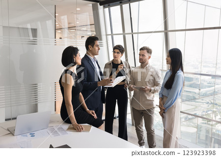 Focused business team stand around mature male leader explaining paperwork 123923398