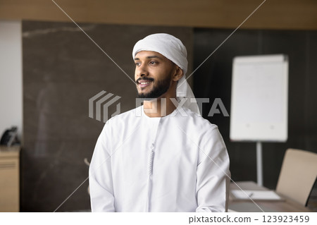 Pensive Arabian entrepreneur looks into distance with smile Pensive Arabian entrepreneur looks into distance with smile 123923459