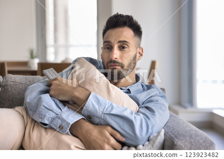Lonely man hugging pillow deeply immersed in watching romantic movie 123923482