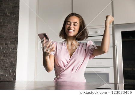 Woman looks at cellphone screen with excited expression Woman looks at cellphone screen with excited expression 123923499