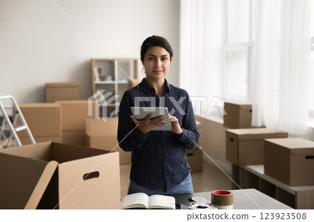 Portrait smiling young female internet shop manager holding digital pad Portrait smiling young female internet shop manager holding digital pad 123923508