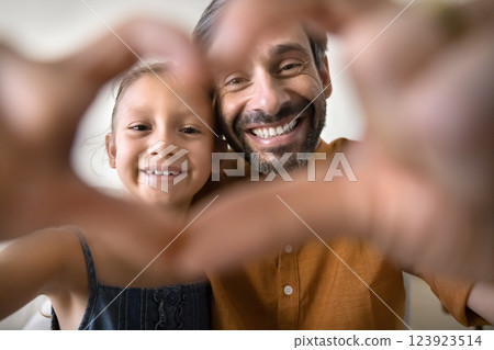 Little girl and father looking at camera through joined fingers Little girl and father looking at camera through joined fingers 123923514