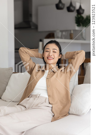 Happy relaxed young Vietnamese woman resting on cozy sofa Happy relaxed young Vietnamese woman resting on cozy sofa 123923521