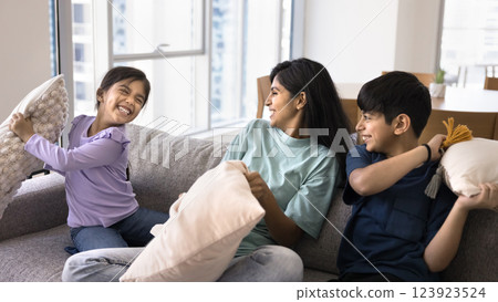 Mom and kids having fun, holding cushions beating each other Mom and kids having fun, holding cushions beating each other 123923524