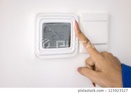 Female hand adjusting temperature on digital thermostat 123923527