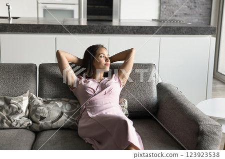 Peaceful woman put hands behind head relaxing seated on couch 123923538