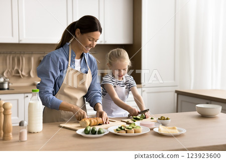 Young woman and little daughter preparing sandwiches for breakfast Young woman and little daughter preparing sandwiches for breakfast 123923600
