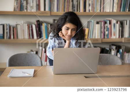 Focused female student lean at desk at library use notebook 123923796