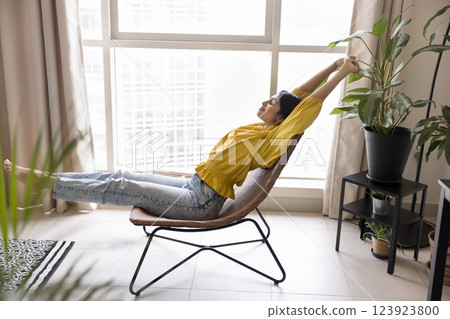 Indian woman relaxing at home leaning on stylish woven chair 123923800