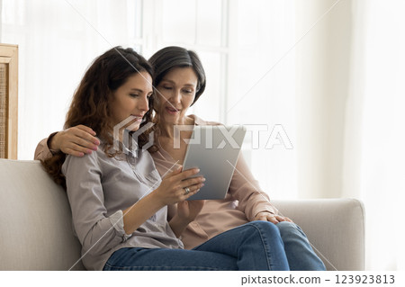 Caring adult daughter with mature mom using tablet on sofa 123923813