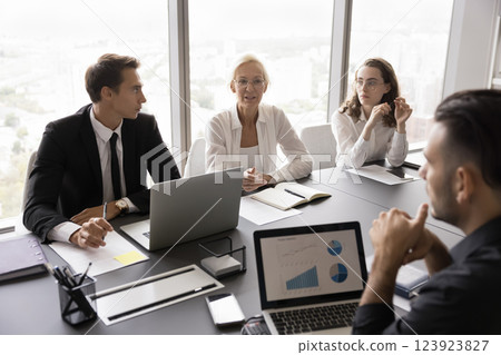 Diverse age business team negotiate at conference desk discuss information Diverse age business team negotiate at conference desk discuss information 123923827
