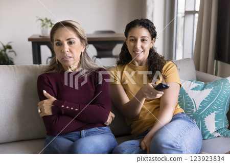 Multigenerational women watch television seated on sofa Multigenerational women watch television seated on sofa 123923834
