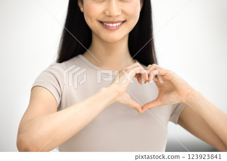 Smiling Asian woman forming heart shape with her hands Smiling Asian woman forming heart shape with her hands 123923841