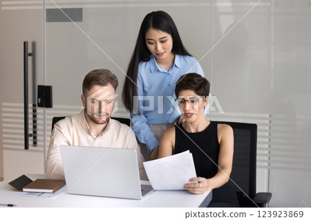 Focused group three diverse multiethnic employees do paperwork using notebook Focused group three diverse multiethnic employees do paperwork using notebook 123923869