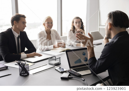 Confident young male explain project strategy to coworkers at boardroom 123923901