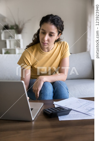 Serious young woman review financial documents at home Serious young woman review financial documents at home 123923940