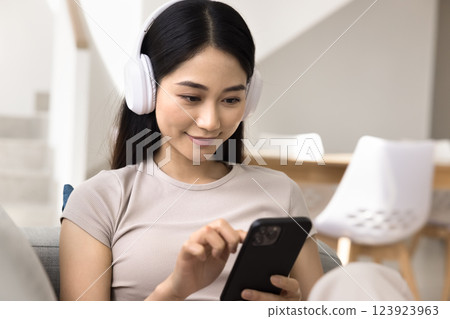 Close up of young Asian woman wear headphones using smartphone Close up of young Asian woman wear headphones using smartphone 123923963