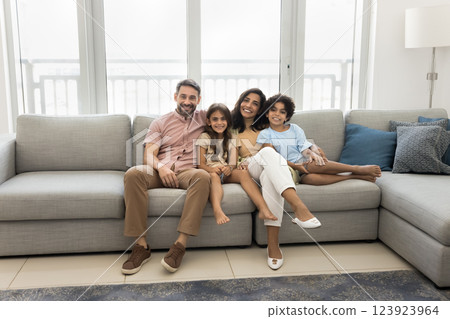 Happy family sitting together on sofa, smiling, looking at camera 123923964