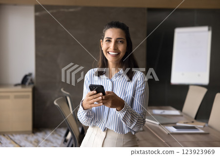 Portrait of smiling businesswoman stands in conference room with smartphone Portrait of smiling businesswoman stands in conference room with smartphone 123923969
