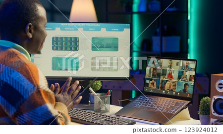 African american male freelancer attends virtual meeting call with clients on laptop, working at home and sharing insight on income statistics. Person listening to video call. Camera A. 123924012