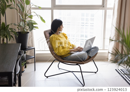 Woman sit comfortably in modern chair holding laptop on lap 123924013